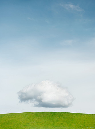 A floating cloud above a green hill by photographer Mieke Boynton